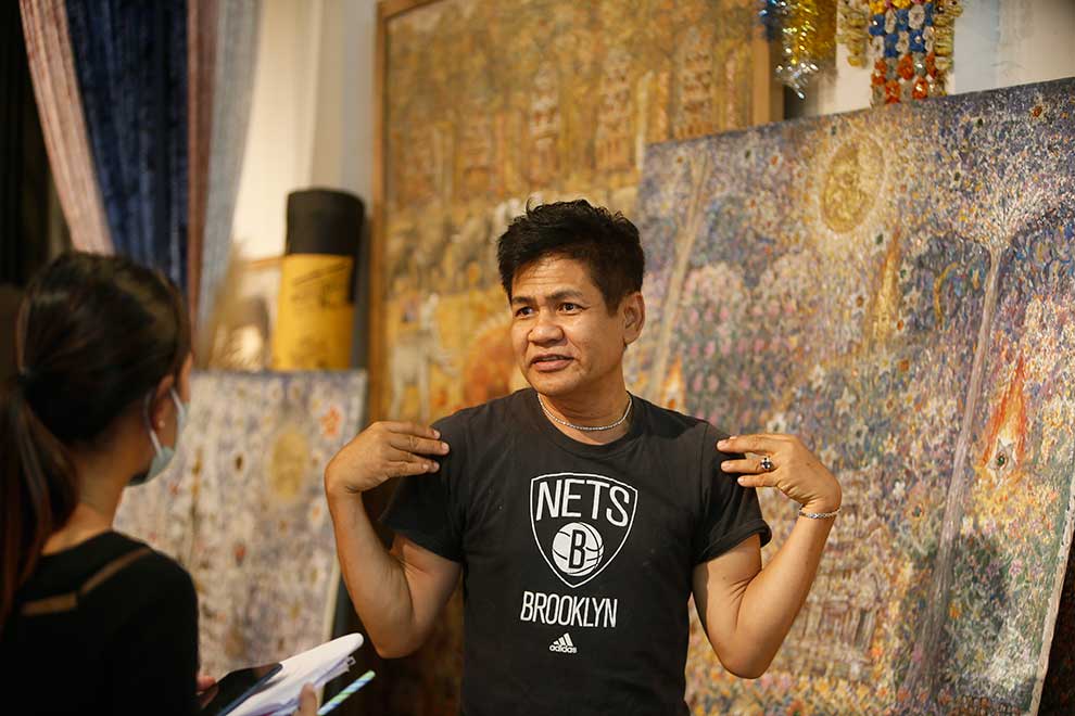 Leang Seckon with his painting titled Star Catcher in the background.