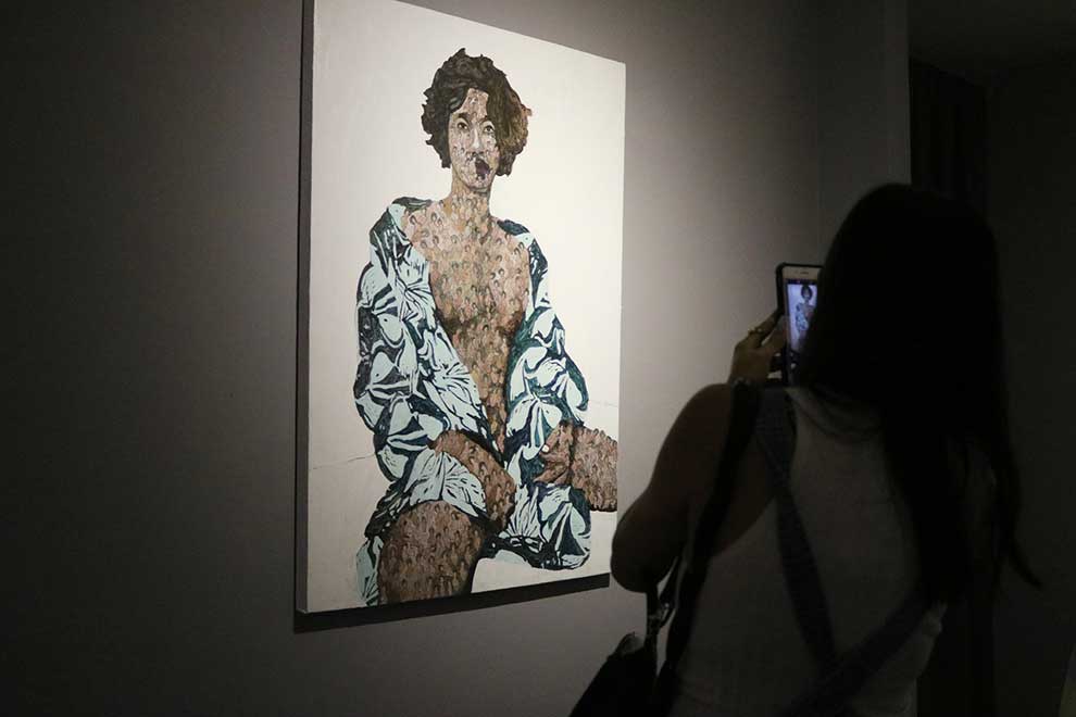 A gallery patron snaps a picture of Ravuth’s self-portrait at STP Cambodia. SUPPLIED