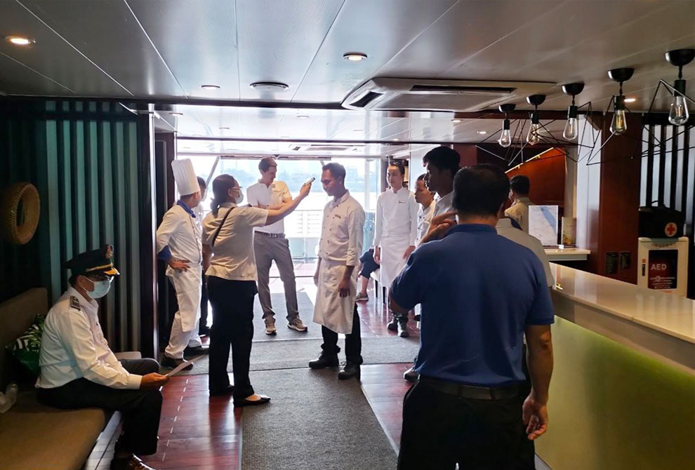 Crew members and tourists on board the CroisiEurope cruise ship take their temperatures before disembarking in Phnom Penh on July 23. ORM BUNTHOEURN
