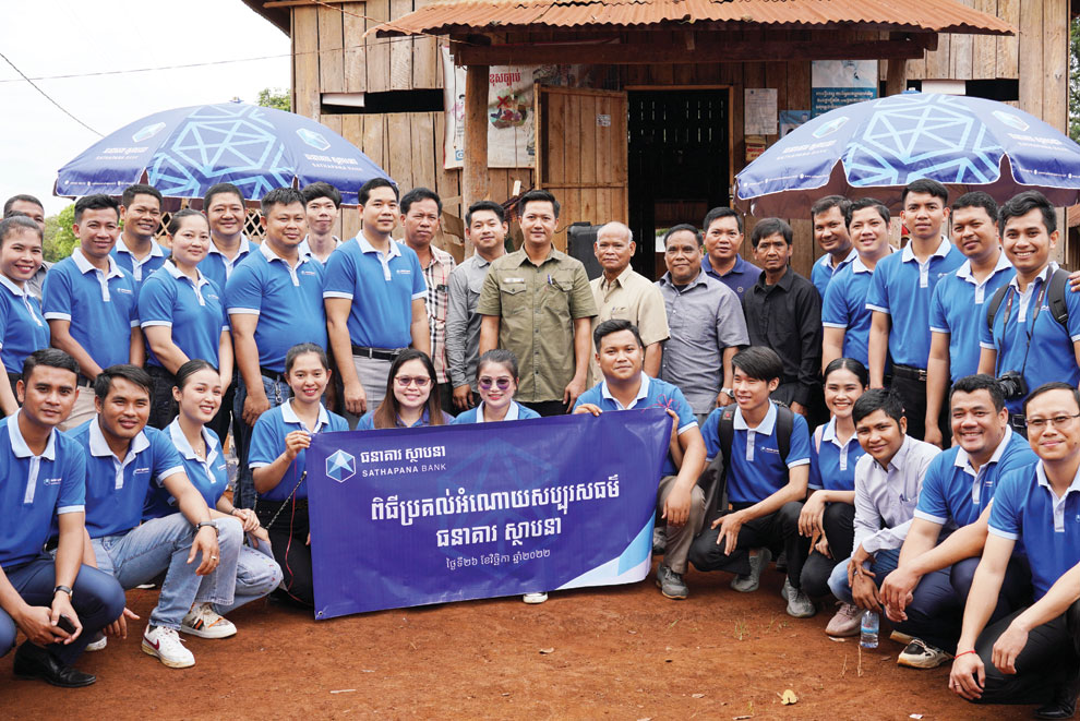 Koy Chamroeunvichea (ninth left), Kieng Tola  (centre) and bank staff join residents. YOUSOS APDOULRASHIM
