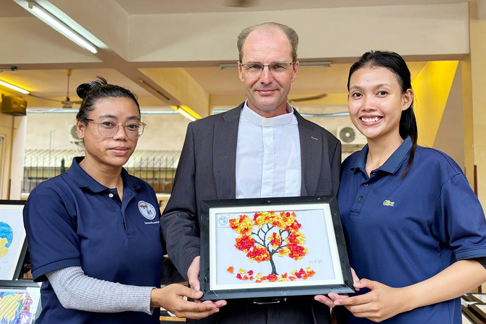 Friar Francois Hemelsdael, leader of Child Jesus Catholic Church, and GSES teachers display one of the artworks made by the autistic children. Supplied