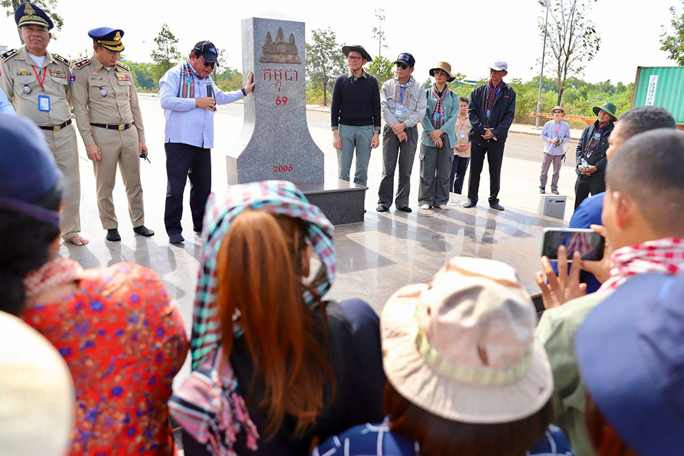 Government spokesperson Pen Bona (black T-shirt, to right of monument) leads visitors on a tour of the northeast region. Supplied