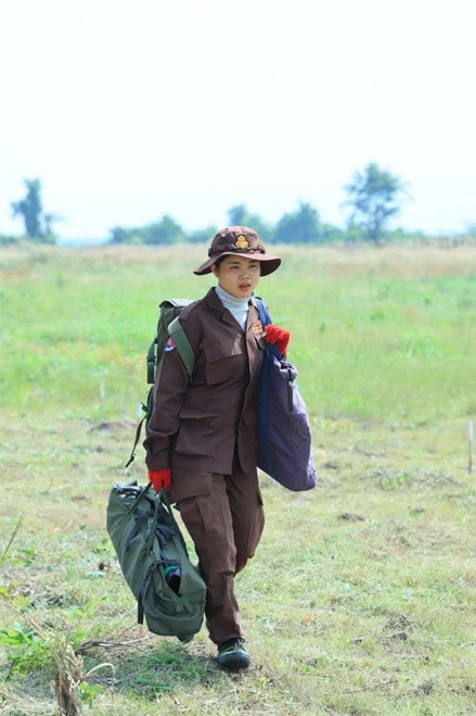 One of CMAC’s dedicated demining operators carries her equipment as she prepares to play her part in returning mine-contaminated land to the people of the Kingdom. CMAC