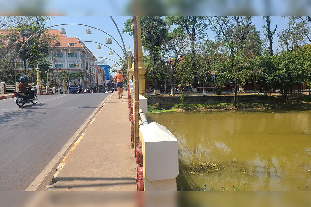 A tourist wanders across a bridge spanning the Siem Reap River. Hong Raksmey