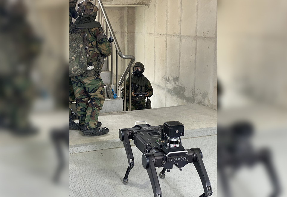 A quadrupedal robot stands behind Army personnel as its operator climbs the stairs. PHOTO: THE KOREA HERALD