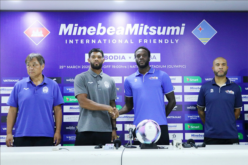 Cambodian captain and defender Kan Mo (centre-left) shakes hands with Aruban defender Nickenson Paul as they stand with their coaches at a March 24 press conference. CPL