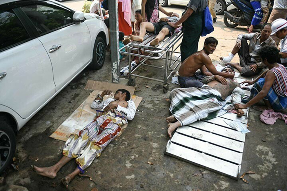 Survivors wait to receive medical attention as they lie on the ground of the compound of a hospital in Naypyidaw on March 28. — AFP