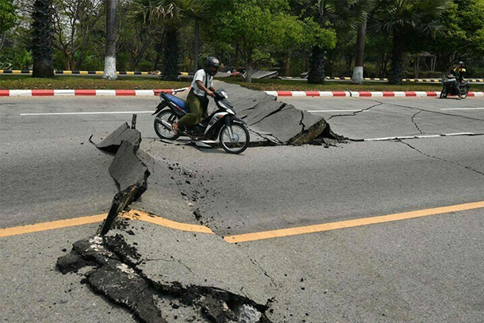 A motorcyclist rides past a damaged road in Naypyidaw on March 28 after an earthquake in central Myanmar.— AFP
