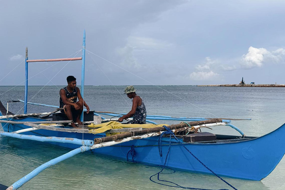 Fishermen Fernan Lozada (left) and Roy Cajamco repairing their boat as construction works continue on Thitu on June 3. PHOTO: THE STRAITS TIMES
