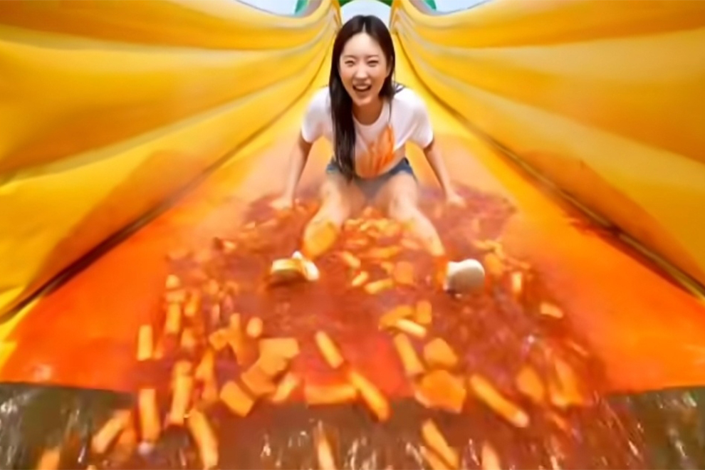 In an AI-generated clip on Instagram, a woman goes down a slide amid a slick of tteokbokki. PHOTO: INSTAGRAM/THE KOREA HERALD
