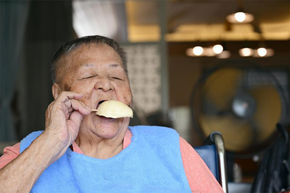 Madam Chua Lian Tee tucking into a stick of durian ice cream brought by her daughter. PHOTO: THE STRAITS TIMES