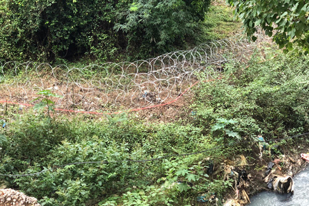 A Thai barbed wire barricade snakes across the ground near the Poipet International Border Checkpoint. Niem Chheng