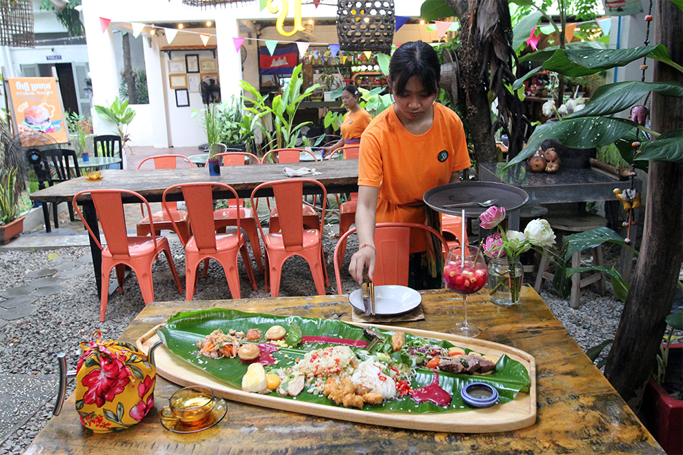A waitress prepares cutlery for a dish made to be shared by two. Hong Raksmey