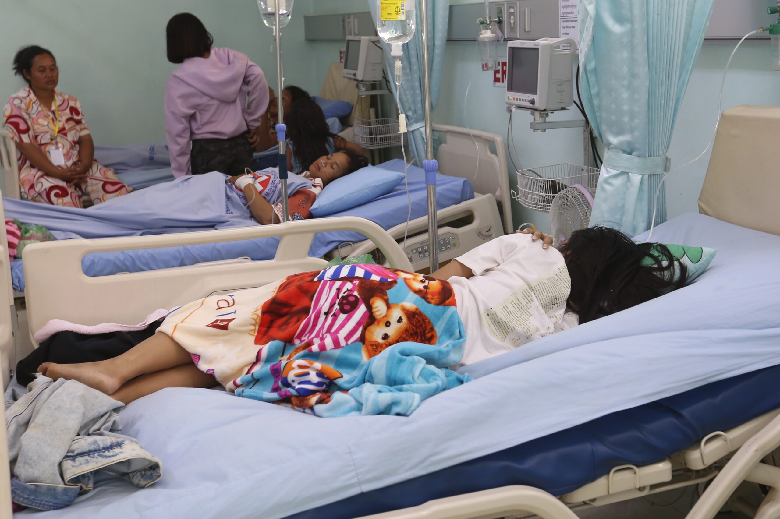 Meas Kimheng (centre) and Phin Ri (farthest) lay in hospital, next to a Thai patient being treated for pneumonia at Poipet Referral Hospital. Hong Raksmey