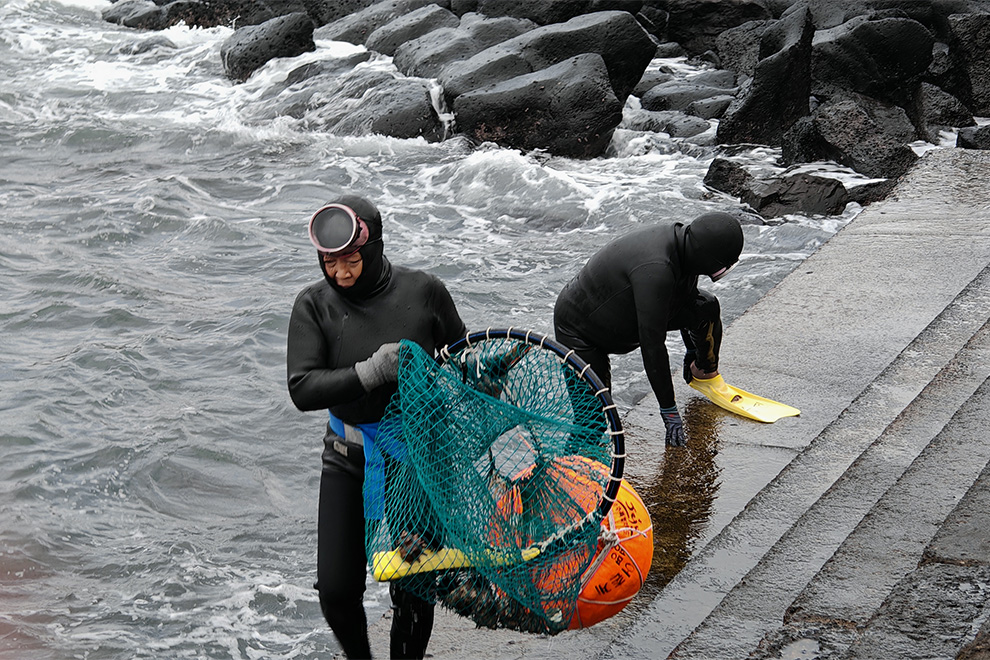 To reach the depths, they strap heavy stone weights to their waists — two or three on good days, more than ten when the currents are difficult — placing significant strain on their backs. Hong Raksmey
