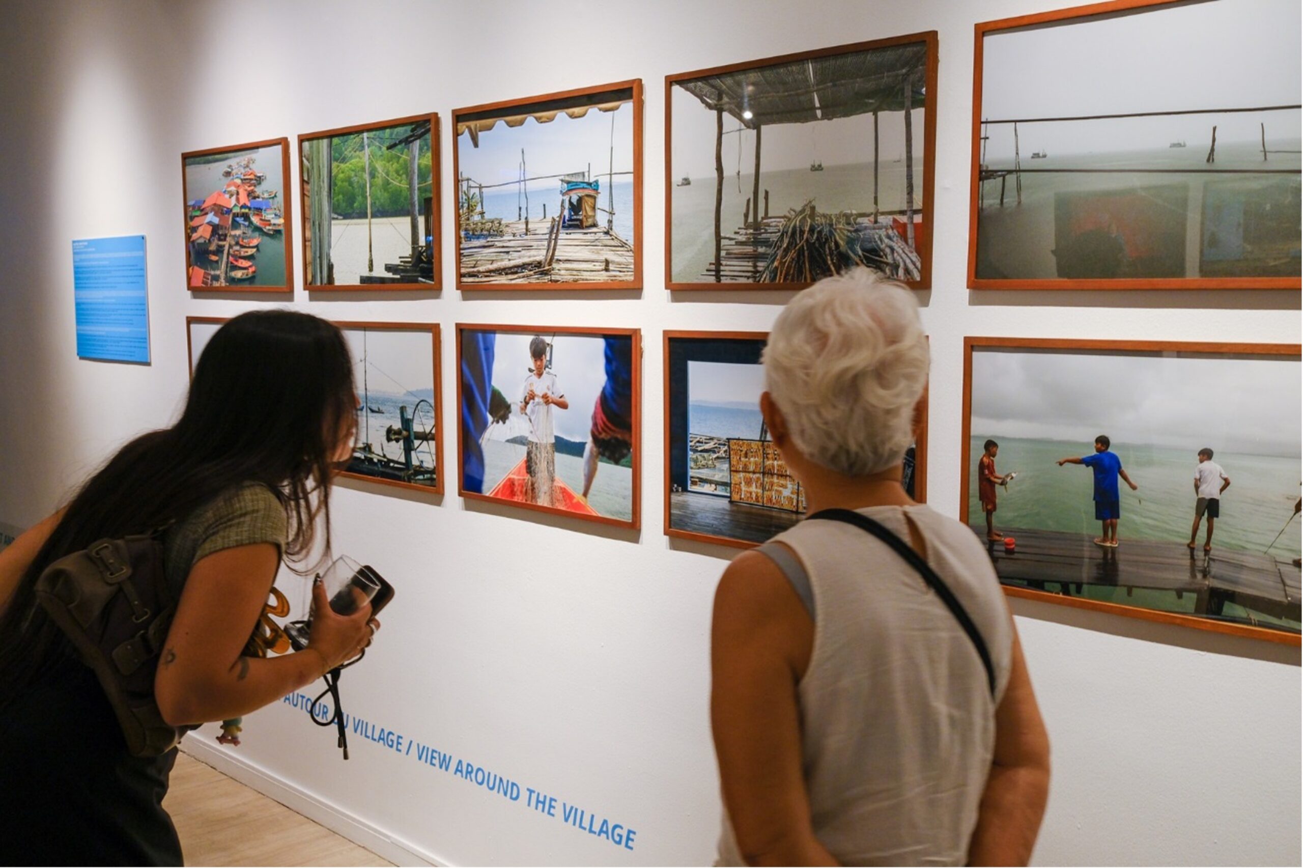 Visitors look closely at Sovan Philong’s photographs of daily life in Avlatan, where he spent months documenting the rhythms of a village suspended above the sea on a network of wooden bridges. IFC/Photo Phnom Penh