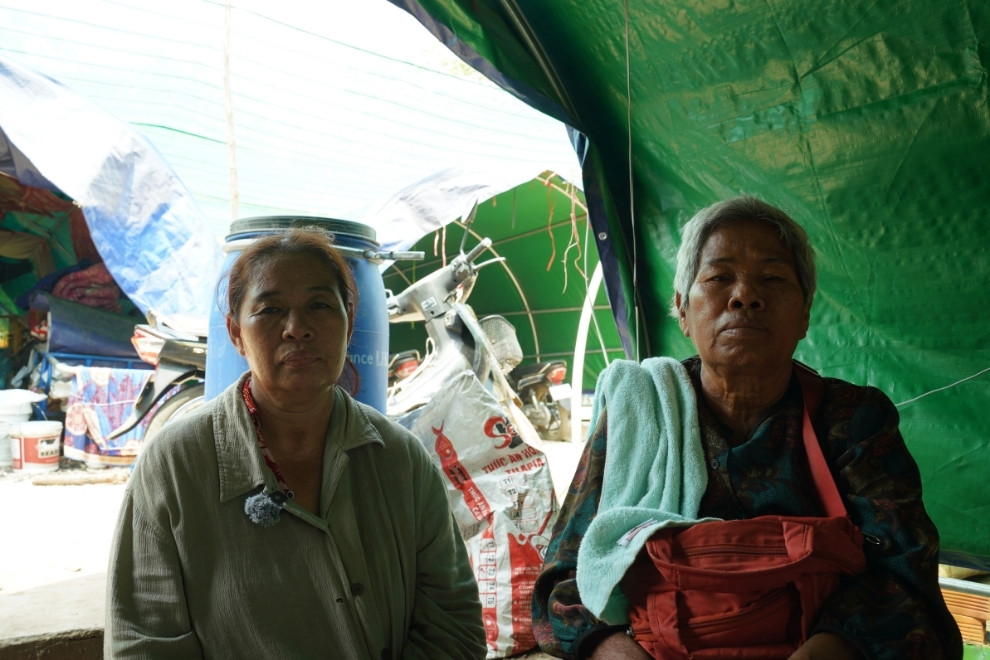 Chhou Toch, 56 (left), and her elderly neighbour sit next to the tent at Wat Kandoul, thinking about a house that was completed less than a month before it was destroyed by Thai shelling. Hong Raksmey
