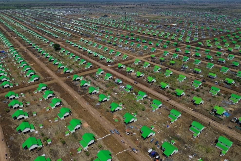 An elderly woman carries her sleeping grandchild, as they prepare to leave the Kandoul camp for their new shelter. Hong Raksmey
