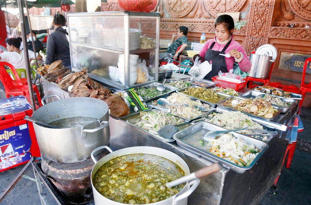 A woman dishing up food buffet-style at Kandal market in February.